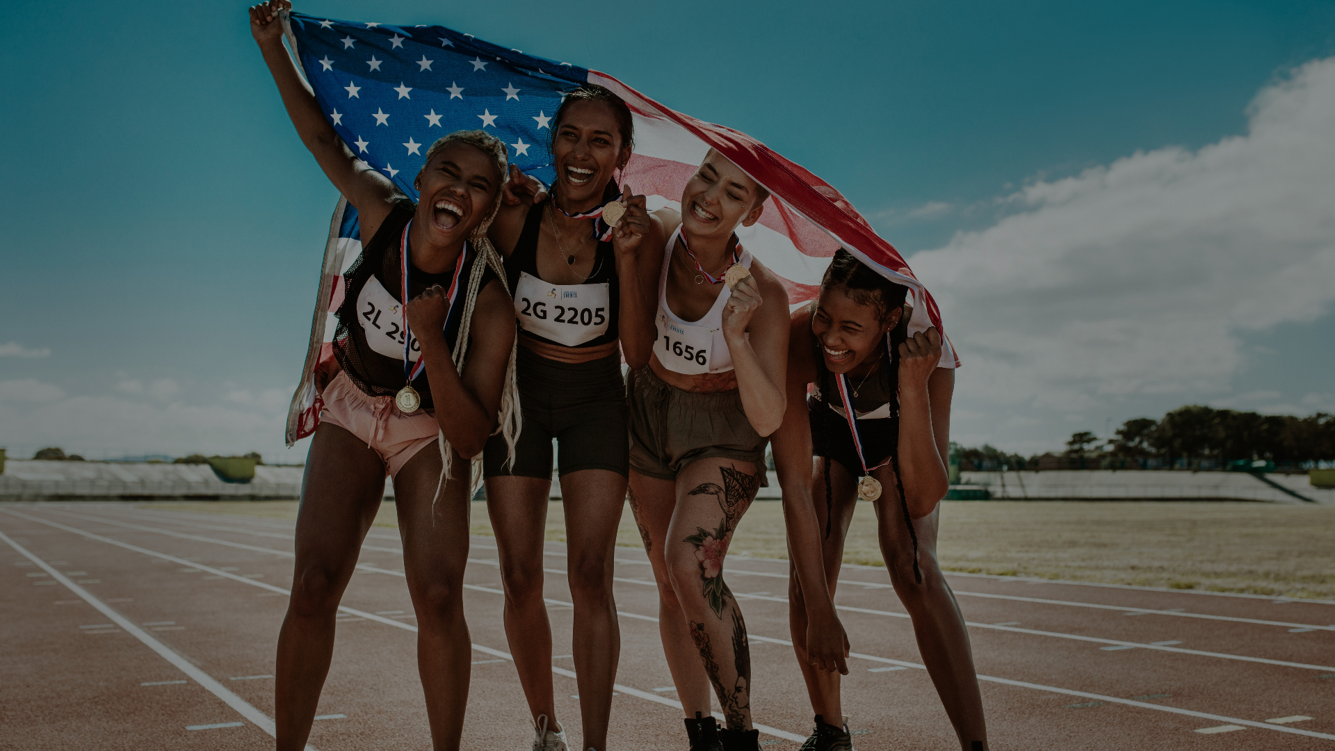 Four women athletes celebrating with the American flag
